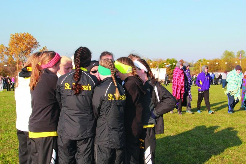 The varsity cross country team huddles together with head coach Karen Moran at the Class 4, Sectional 4 meet Nov. 9. photo by Mary Hilliard