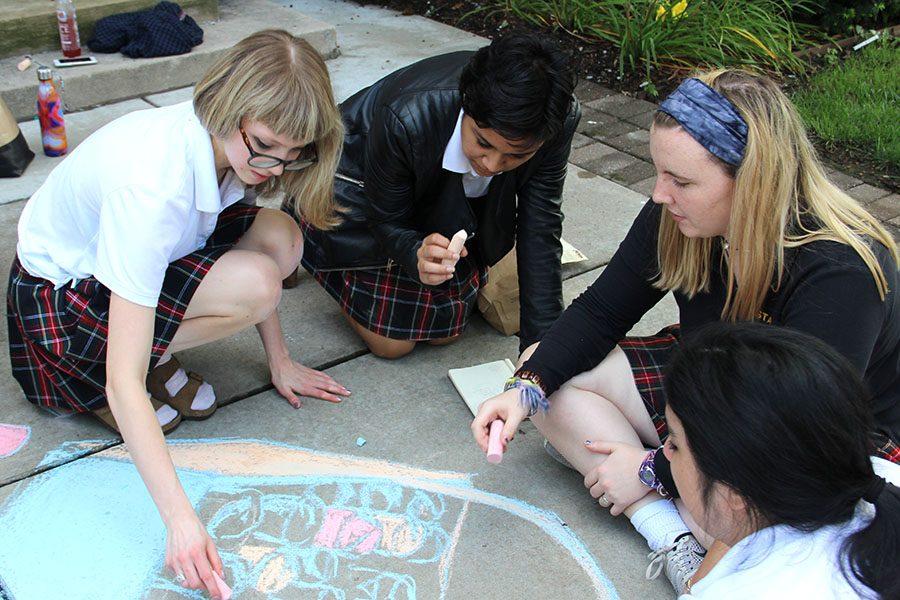 Senior Ellie Grever, from left, junior Yasmeen Mir and junior Annie Mullen contribute to their advisorys chalk drawing. Grever, Mir and Mullen are members of the Reynolds advisory. photo by Anna Louise Sih