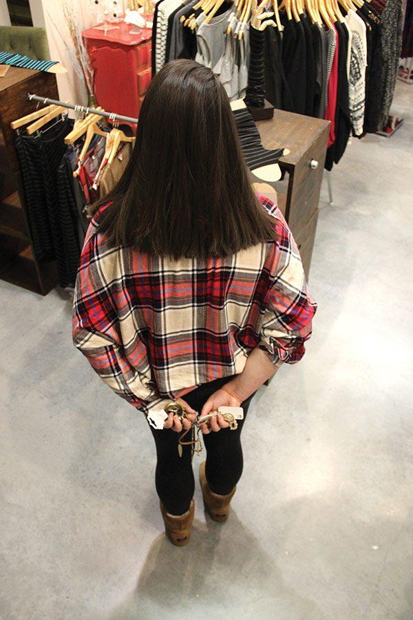 An anonymous girl hides necklaces and bracelets behind her back in an attempt to steal them from the store they are from. photo by Anna Louise Sih