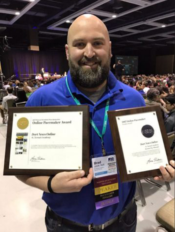 Dart and Teresian adviser Brad Lewis holds up the Darts Pacemaker finalist award and award winner plaques. Lewis attended the NHSJC (National High School Journalism Convention) in Seattle, WA to receive the award winner plaque for STA. photo courtesy of Jim McCrossen, Blue Valley Northwest High School