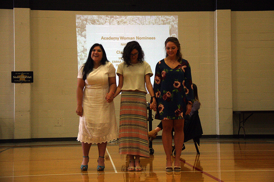 Seniors Isabelle Gatapia, from left, with Emma Kate Callahan and Molly Burns hold hands as the 2017 Academy Woman is announced at the awards ceremony held in the Goppert Center April 25. photo by Cassie Hayes