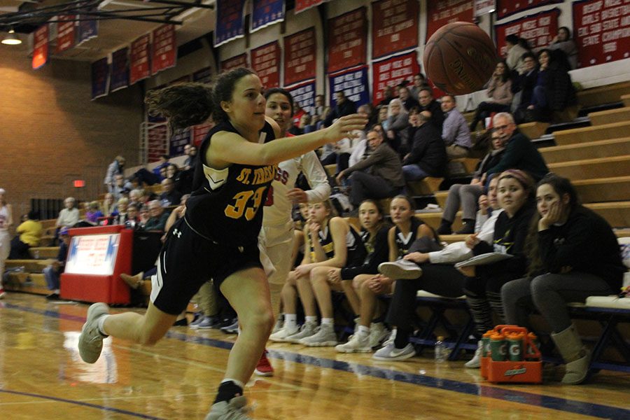 Sophomore Demi Spini reaches for the ball before it goes out of bounds Jan. 16.  STA lost to Bishop Miege, with a final score of 49-72. photo by Madeline Loehr