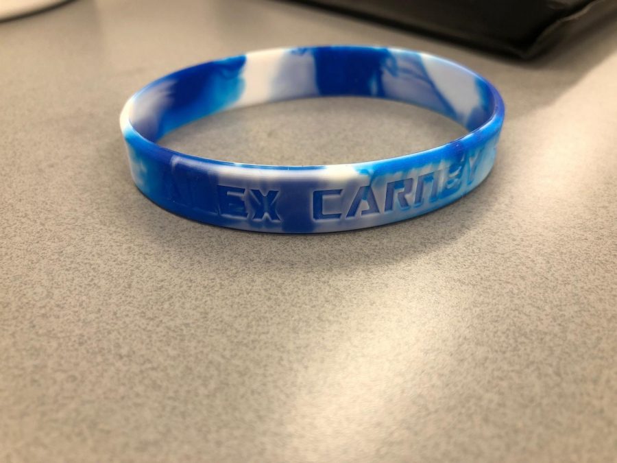 Sophomore Mia Falcon sold bracelets in memory of Alex Carney. Her bracelet sits on a table. photo courtesy of Mia Falcon