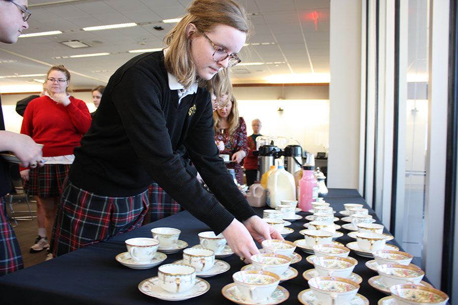 Senior Maura Graham grabs a teacup from the table at the CSJ tea party March 1 in WIndmoor. CSJ club moderator Jennifer Greene helped prep for the event. photo by Trang Nguyen