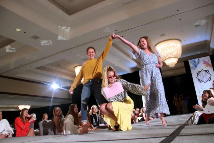  Seniors Reece Knudson, from left, Isabel Shorter and Victoria Parsons walk down the catwalk during the Senior Fashion Show Mar. 31. Shorter dropped to the floor while  Knudson and Parsons raised their hands and walked over her. photo by Tess Jones