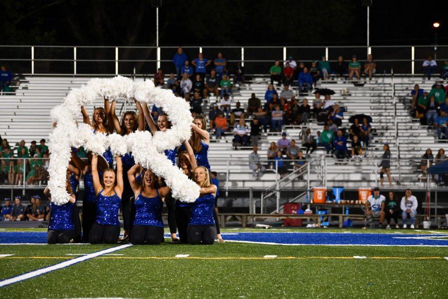 The varsity dance team puts their pom-poms into the formation of an “R” for Rockhurst High School Sept. 20. The seniors choreographed the routine over the course of a month. photo by Katie Massman