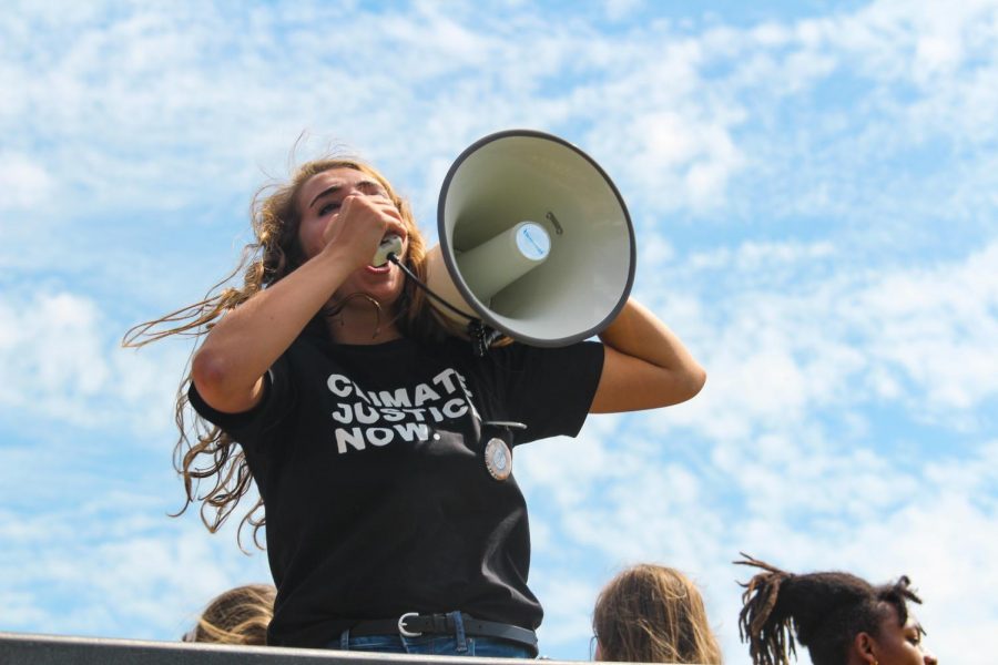 A Sunrise Movement volunteer leads a “Green New Deal” chant with a megaphone Sept. 20. Protesters chant “fossil fuels have got to go” while marching from James A Theis Park to UMKC. photo by Amy Schaffer