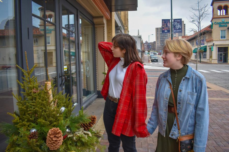 Juniors Mady Mudd and Maggie Dodderidge hold hands and look inside a shop on the Country Club Plaza Dec. 8. Couples can shop for festive items and food during the season. photo by Lilly Frisch