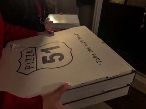 Seniors Isabella Dougherty and Yalei Wilcox delivering Pizza 51 to an auction participant Friday Nov. 20. Both Dougherty and Wilcox say that they volunteered because STA has done so much for them and they want to give back to that community. photo by Josie Fox