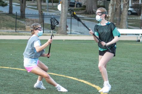 Sophomore Maggie Reintjes guards junior Grace Uecker during a varsity lacrosse practice drill March 10. A command was yelled by one of the coaches giving the players instructions as the offensive players tried to move towards the lacrosse goal.