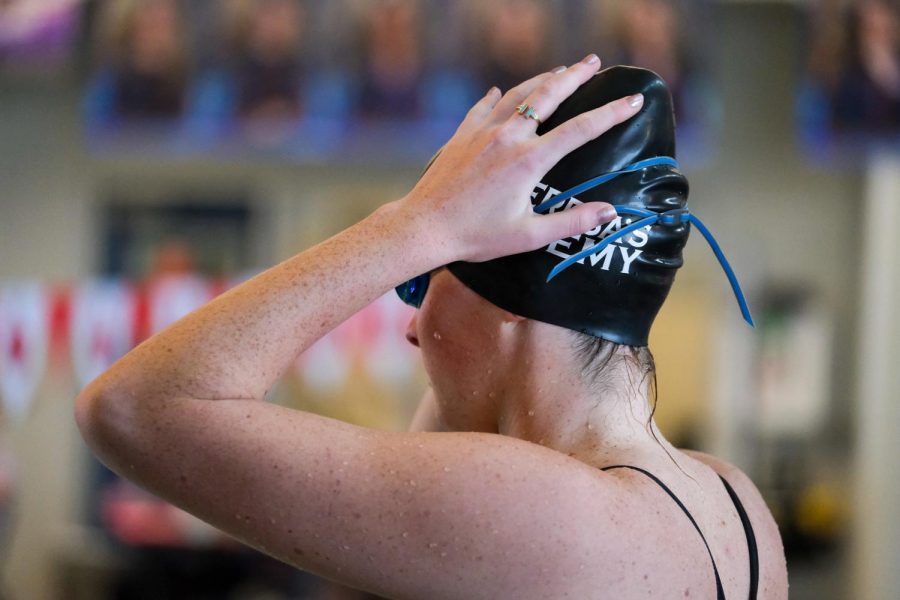 Senior Annie Freeman fixes her swim cap to get ready for her race. The varsity finals started at 12:30 p.m. on Saturday.