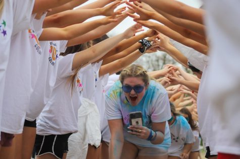 Senior Caroline Thrun runs through the tunnel of students. The senior class won a tailgate before the Walk of Fame, where they got to douse psychology teacher Nicolas Shump in colored powder.