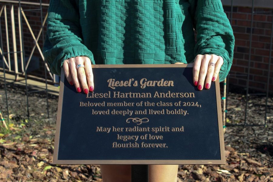 Junior Anne Rinella stands with the garden plaque, honoring Liesel Anderson. photo by Charlotte Malone
